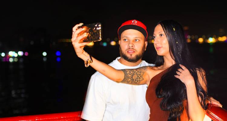 Couple prenant un selfie la nuit avec des lumières colorées en arrière-plan.