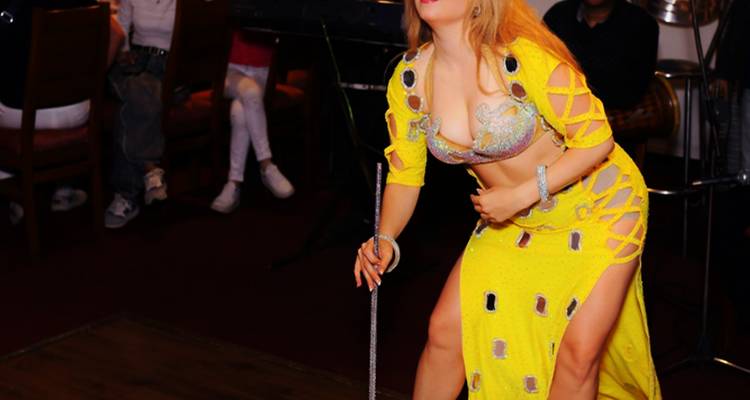 Un interprète dans une tenue jaune vif, tenant une canne, probablement pendant un spectacle de danse.