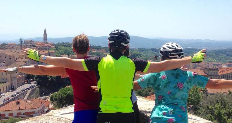 Trois cyclistes profitant d'une vue panoramique, les bras largement étendus.
