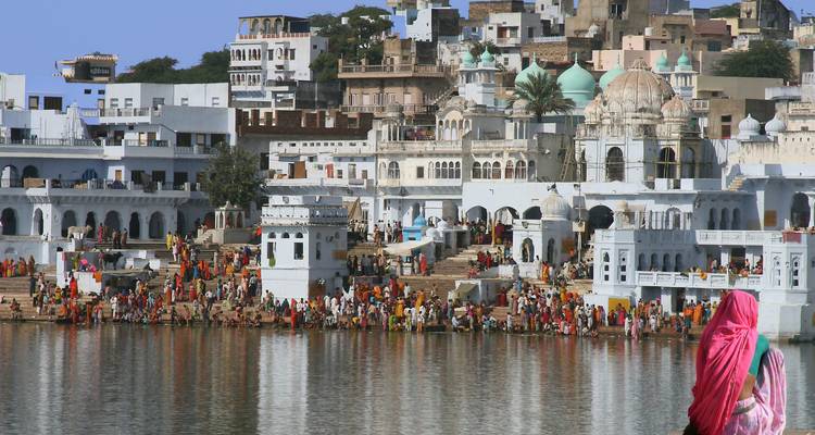 Menschenmengen versammelten sich an einem See in einer lebendigen Stadt mit kuppelförmigen Tempeln.