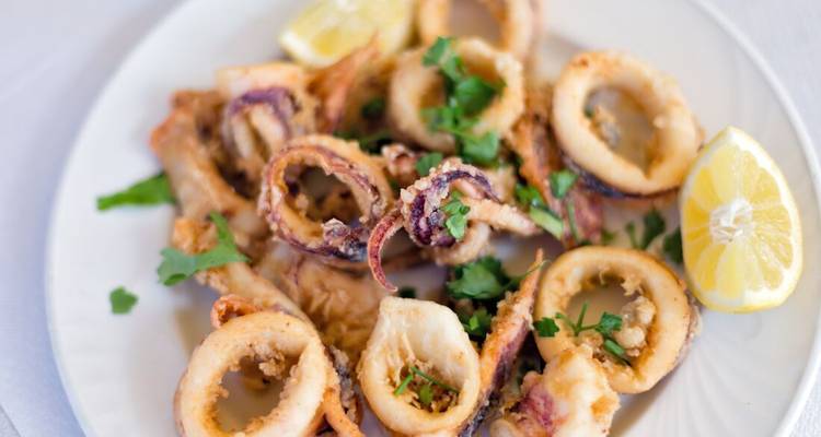 Plato de calamares fritos y crujientes garnished con limón y hierbas
