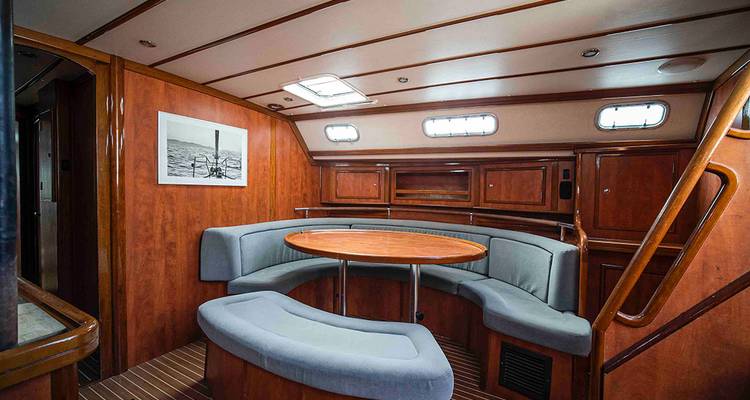 Salón de yate con paneles de madera, asientos curvos y tragaluz