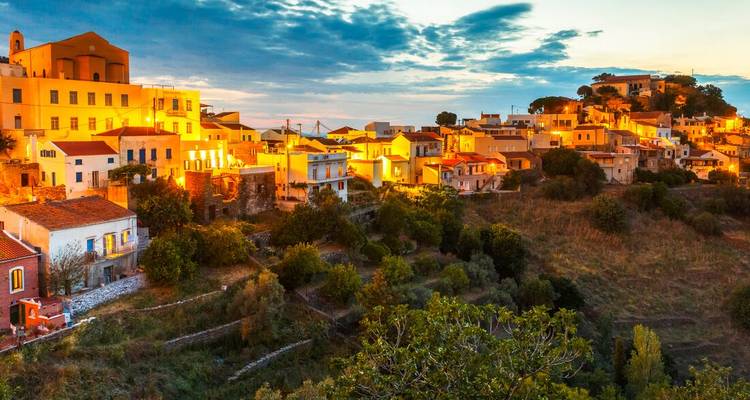Pueblo en la ladera brillando con luces cálidas al atardecer contra un cielo dramático