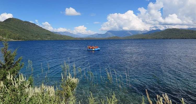 Menschen auf einem Boot in einem großen See mit Bergen