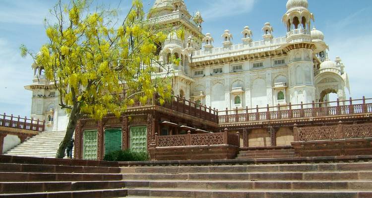 Un mausoleo de mármol blanco rodeado de escalones y un árbol en flor.