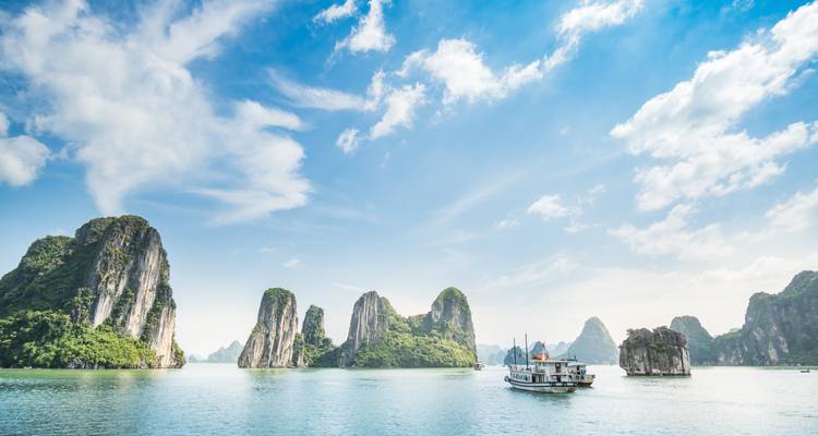 Boat cruising in Halong Bay with limestone karsts.