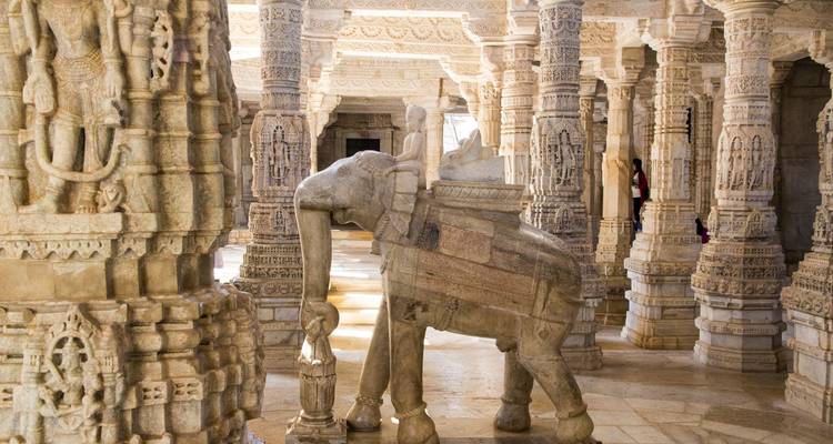 Intricately carved stone pillars inside a temple with low lighting.