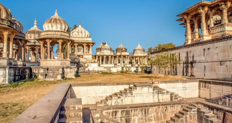 Historic site with domed pavilions and stone steps, under a bright sky.