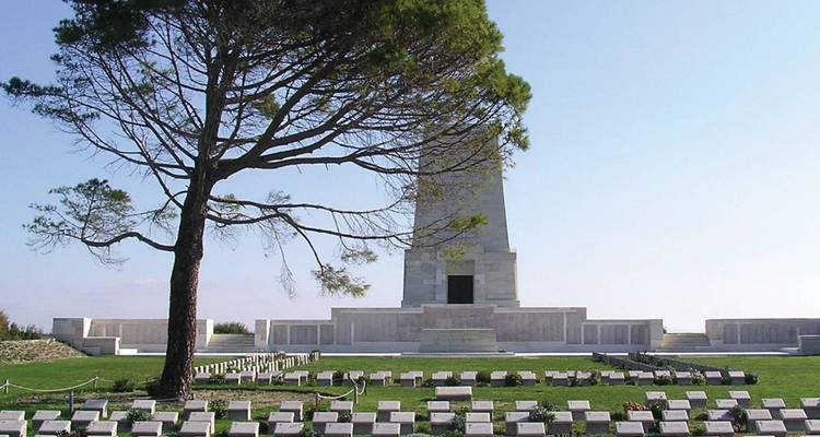 Gallipoli memorial monument surrounded by greenery and plaques.