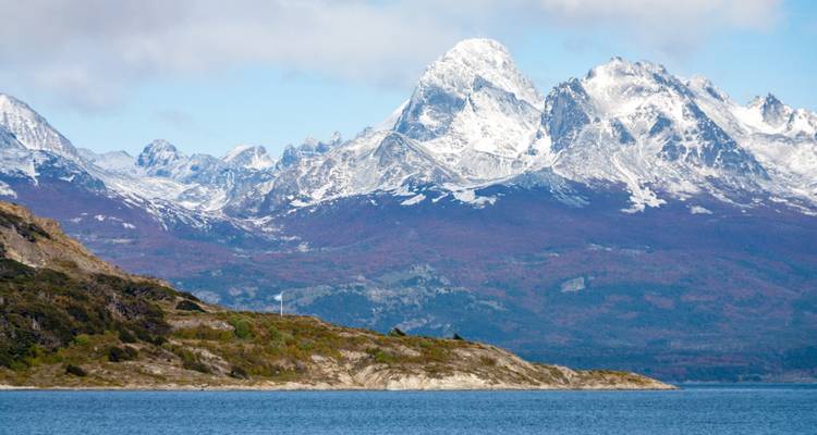 Schneebedeckte Berge mit Blick auf ein ruhiges Gewässer.
