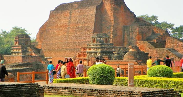 Ruines anciennes avec visiteurs et verdure.