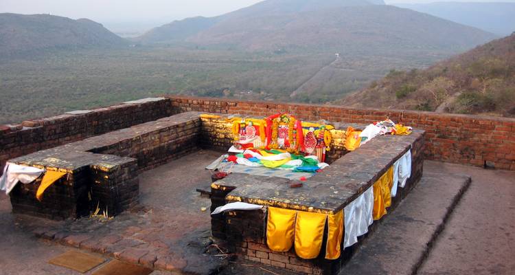 Site sacré avec offrandes colorées et vue sur la montagne.