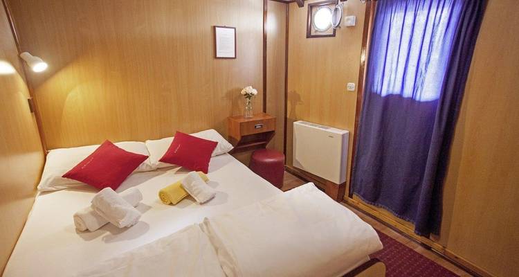 Cabine douillette avec lit double et fenêtre sur un bateau.