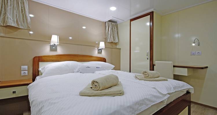 Cabine de yacht avec un lit soigneusement fait et une décoration moderne.