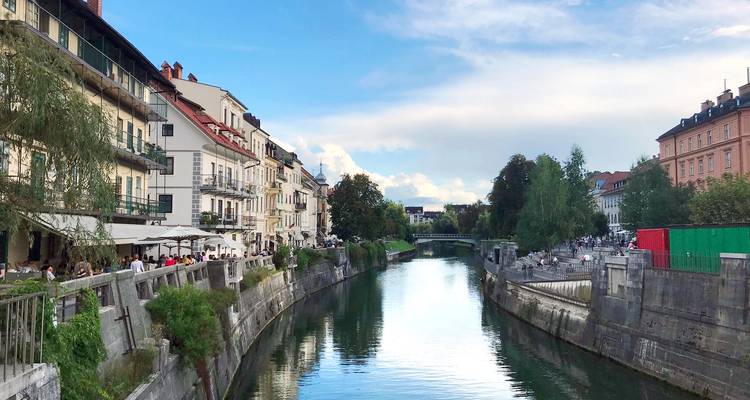 Les cafés riverains verdoyants de Ljubljana et ses façades pastel se reflétant dans les eaux calmes et émeraude de la Ljubljanica.