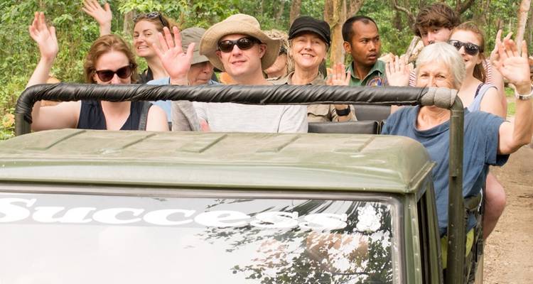 Gruppe von Menschen, die aus einem Safari-Fahrzeug winken.