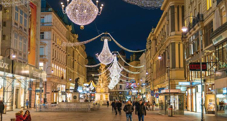 Los elegantes candelabros de luces cuelgan sobre la calle Graben de Viena mientras los compradores vespertinos pasean por debajo.