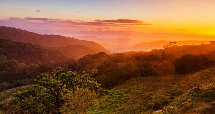 Coucher de soleil dans les collines du Costa Rica avec des couleurs chaudes et des paysages vallonnés.