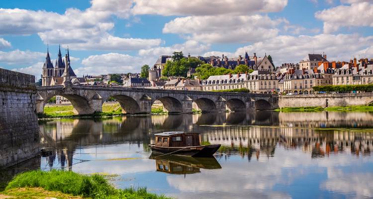 Pont en pierre et skyline riverain de Blois se reflétant dans la Loire calme avec un bateau au premier plan