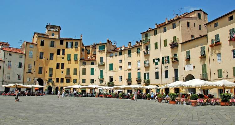 Ovaal Piazza dell'Anfiteatro in Lucca omringd door gele gebouwen met terrasjes en blauwe lucht