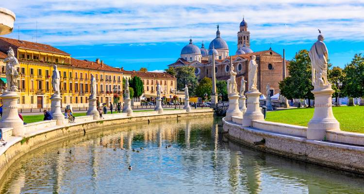 Prato della Valle kanaal met standbeelden en koepelbasiliek onder een stralend blauwe hemel in Padua.
