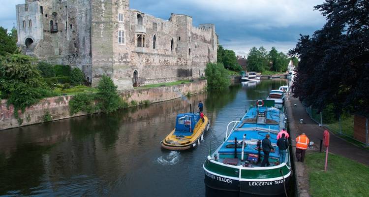 Smalschipverkeer passeert middeleeuws rivierkasteel in het VK op een bewolkte dag