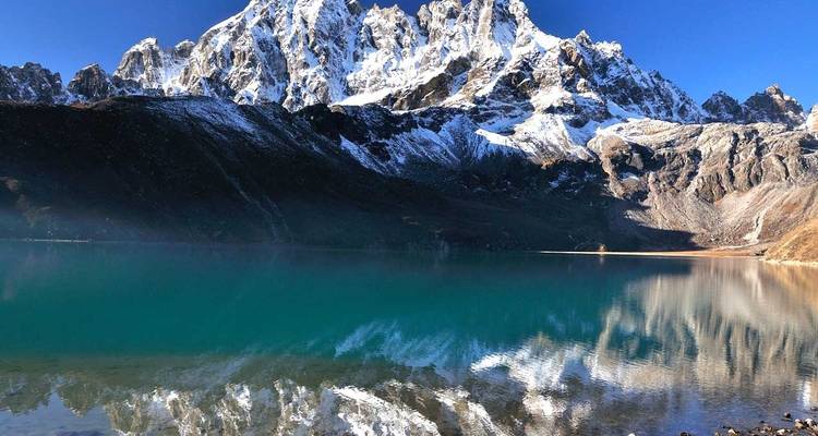 Gebirgszug spiegelt sich in dem klaren blauen Wasser eines Sees wider.