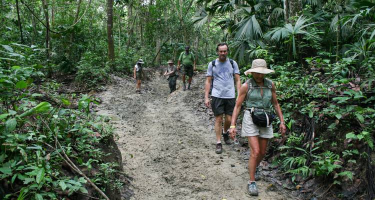 Groep mensen die door een modderig bospad wandelt.