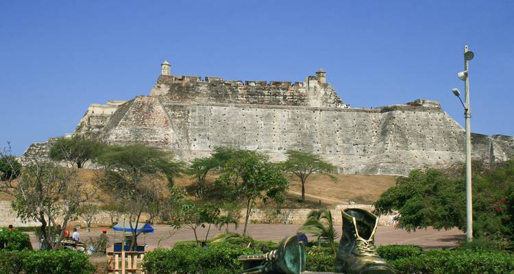 Grote vestingmuur met een standbeeld van grote laarzen ervoor.