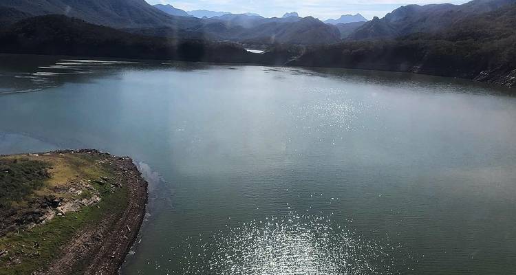 Lac serein avec des montagnes en arrière-plan sous un ciel dégagé.
