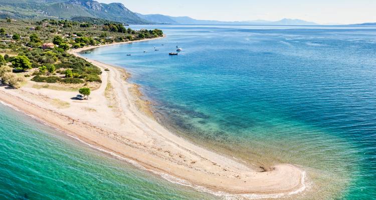 Luftaufnahme eines schmalen Strandes mit klarem blauen Wasser.