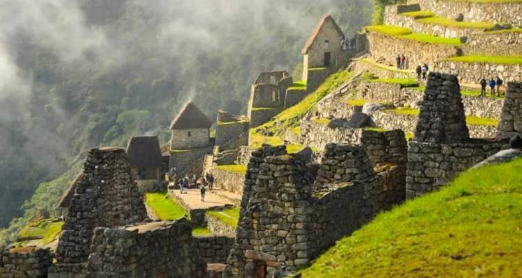 Stone terraces and houses of an Inca ruin complex perched on a misty green mountainside