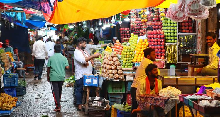Marché de fruits et légumes animé avec des gens qui font leurs courses et qui vendent.