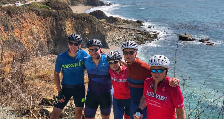 Group of cyclists posing by the coast.