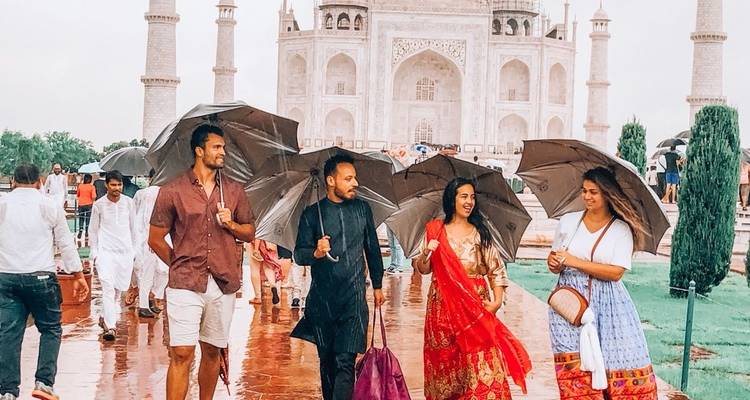 Des visiteurs tenant des parapluies marchent devant le Taj Mahal.