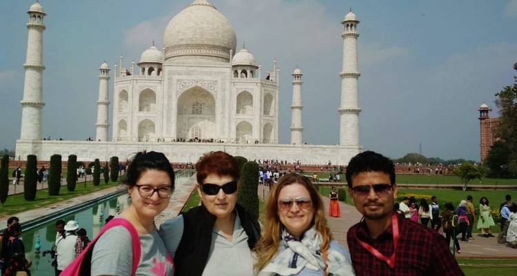Petit groupe de touristes debout devant le Taj Mahal.