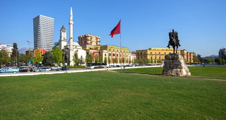 Central square featuring a monument, mosque, and tall buildings.