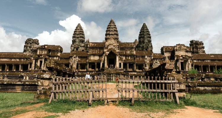Complejo de templos de Angkor Wat con árboles y un cielo nublado.