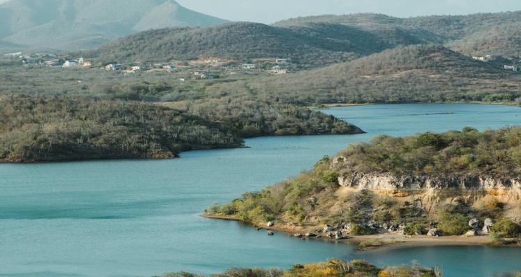 Vista panorámica de un cuerpo de agua rodeado de colinas y vegetación exuberante.
