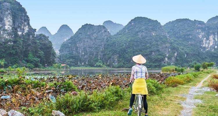 Person, die mit einer malerischen Kulisse aus Kalksteinbergen und üppigem Grün Fahrrad fährt.