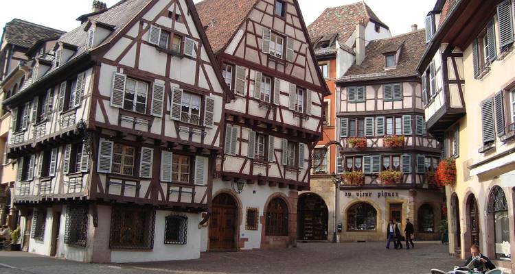 Maisons traditionnelles à colombages sur une place historique de ville française.