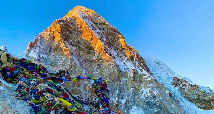 Sommet de montagne illuminé par la lumière du soleil avec des drapeaux de prière.