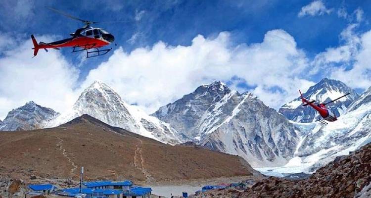 Twee helikopters vliegen over een bergachtig besneeuwd landschap met blauwe luchten.