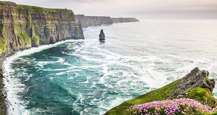 Panoramic view of the Cliffs of Moher with vibrant green and blue hues.