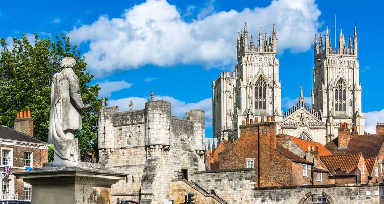 Historic city structures with a statue and cathedral in view.