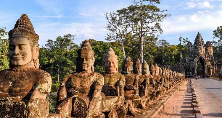 Ancient statues line a temple entrance with lush greenery.