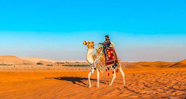 Persoon die op een kameel rijdt in de woestijn.