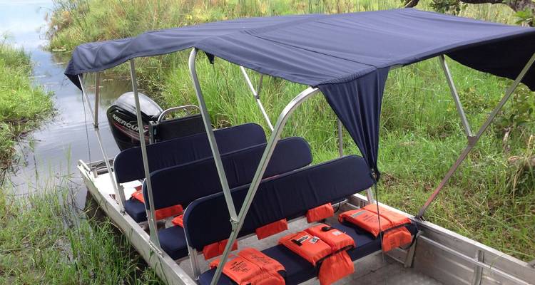 Pequeño bote con área de asientos y chalecos salvavidas sobre hierba verde fresca.