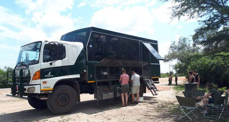 Group of people gathered around a large safari truck.