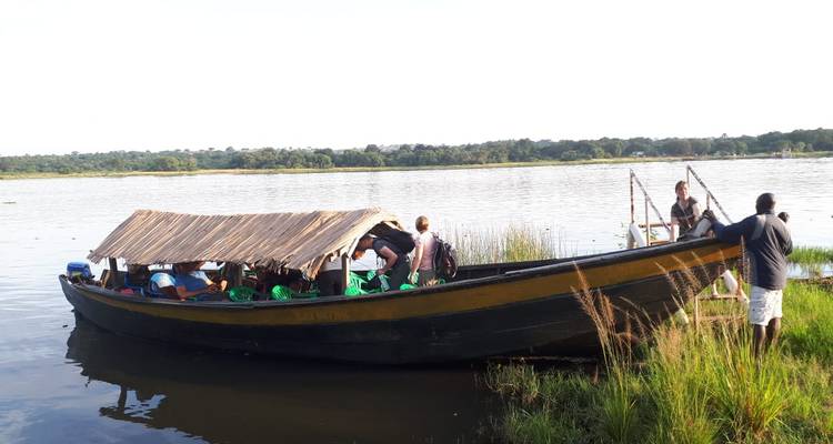 Boat with roof carrying people on a lake.